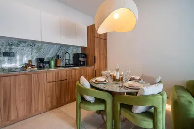 a kitchen with a table with green chairs and aendant light at Magic Day 2BR Private Sauna, Jacuzzi, Projector in Seminyak