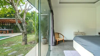 a bedroom with a bed and a view of a yard at Villa Alana, 3 BR Villa in Kerobokan in Mantaak