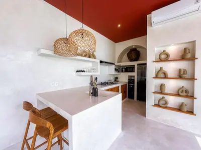 a kitchen with a white counter and wooden chairs at Villa Nabu - Serene Tropical Escape in Heart of Seminyak in Seminyak