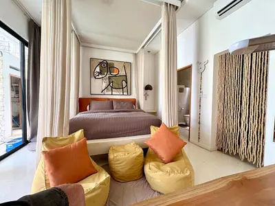 a bedroom with a bed and two yellow chairs at Casa Bali in Kerobokan