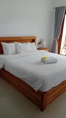 a bedroom with a large bed with white sheets at wiratijenengguesthouse in Kerobokan