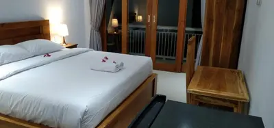 a bedroom with a white bed and a window at wiratijenengguesthouse in Kerobokan
