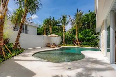 a swimming pool in the backyard of a house with palm trees at Villa Twin 1 by BaliSuperHost in Seminyak