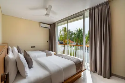 two beds in a room with a large window at Villa Twin 1 by BaliSuperHost in Seminyak