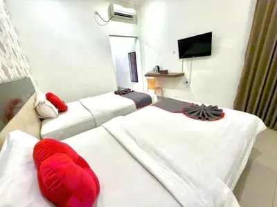 a hotel room with three beds and a flat screen tv at Famora Stay Kuta Bali in Ngurah Rai International Airport