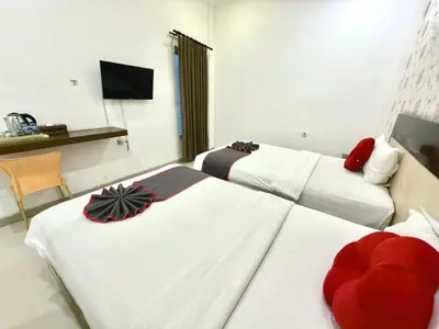 a hotel room with two beds and a television at Famora Stay Kuta Bali in Ngurah Rai International Airport