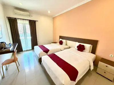 a hotel room with two beds and a desk at Famora Stay Kuta Bali in Ngurah Rai International Airport