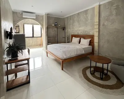 a bedroom with a bed and a table and a couch at ET Living Cozy Studio Room in Kerobokan