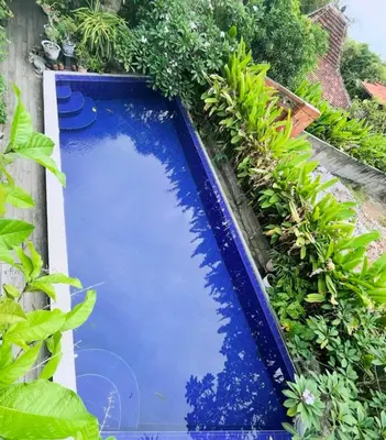 a blue swimming pool in a garden with plants at ET Living Cozy Studio Room in Kerobokan