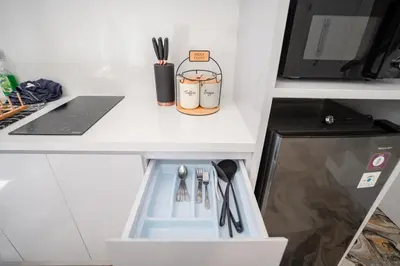 a white kitchen counter with a drawer with utensils at Lumbung Sari Studio in Ngurah Rai International Airport