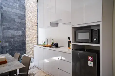 a kitchen with white cabinets and a black microwave at Lumbung Sari Studio in Ngurah Rai International Airport