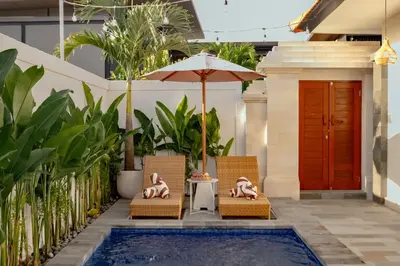a couple of chairs and an umbrella next to a pool at A Better Villa 3BR Seminyak 5min Beach Bintang in Seminyak