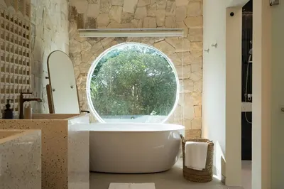 a bathroom with a large tub and an oval window at Villa Tiga by BaliSuperHost in Canggu