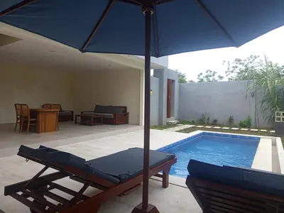 a blue umbrella sitting next to a swimming pool at villa reyray in Jimbaran