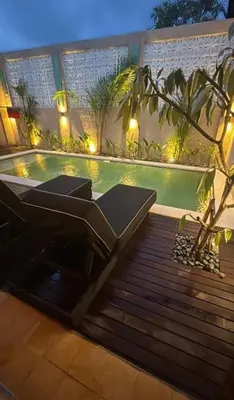 a swimming pool with a chair next to a house at Joglo Raera Bali by Allura in Seminyak