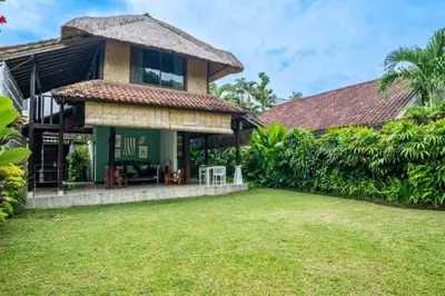 a house with a thatched roof and a yard at Calinda Tropical 1 BR Bungalow With Garden View in Seminyak