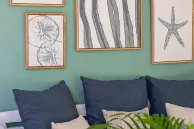 a living room with blue pillows and pictures on the wall at Calinda Tropical 1 BR Bungalow With Garden View in Seminyak