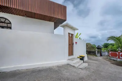 a white building with a wooden door on it at Palm Sugar Villa - Stylish 3BR Retreat with Pool in Jimbaran
