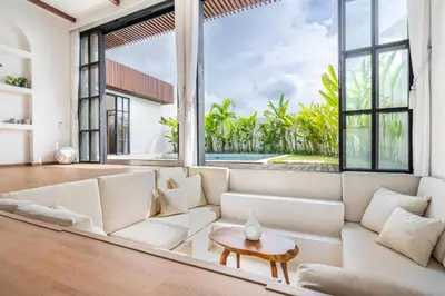 a living room with a white couch and large windows at Palm Sugar Villa - Stylish 3BR Retreat with Pool in Jimbaran