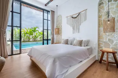 a white bedroom with a bed and a large window at Palm Sugar Villa - Stylish 3BR Retreat with Pool in Jimbaran