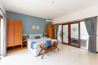 a large bedroom with a large bed and a chair at Gahyaka Comfortable 2 BR Deluxe Private Pool Villa in Seminyak