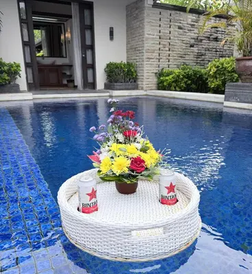 a table with flowers on it next to a swimming pool at Alex Villa Bali in Seminyak