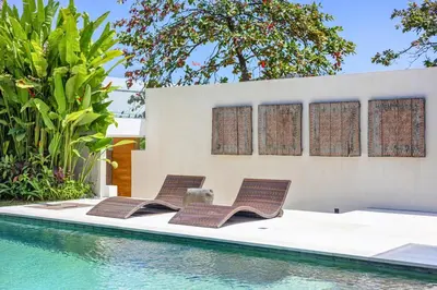 a group of chairs sitting next to a swimming pool at Zen Retreat 3BR Japanese Inspired Oasis with Pool in Canggu