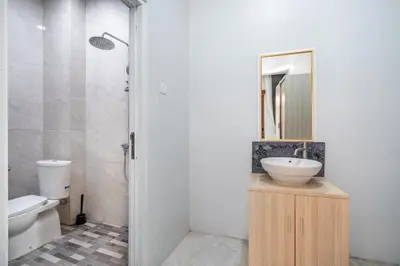a bathroom with a sink and a toilet and a mirror at Collection O Dukuh Segara Guest House in Balian