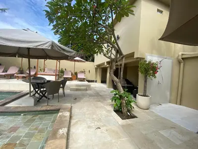 a patio with a table and chairs and a tree at arjuna house in Seminyak