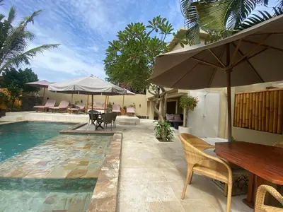 a pool with a table and chairs and an umbrella at arjuna house in Seminyak