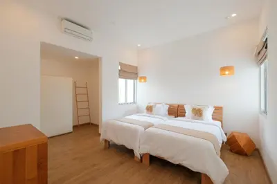 two beds in a room with white walls and wooden floors at Villa Turkuaz in Seminyak