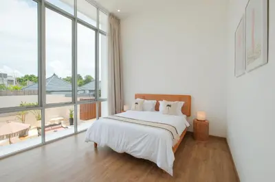 a white bedroom with a bed and large windows at Villa Turkuaz in Seminyak