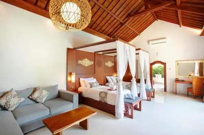 a bedroom with a bed and a couch in a room at Eksha Comfortable 3 BR Private Pool Villa in Jimbaran