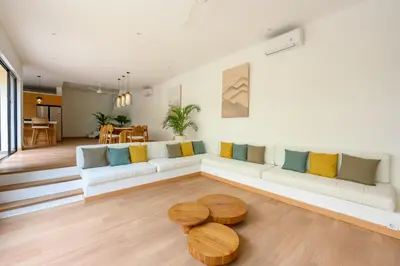 a living room with a white couch and wooden tables at Spacious 4BR Family Pool Villa in Sanur