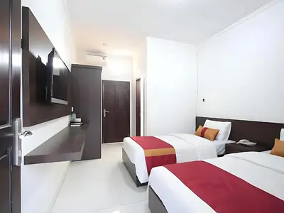 a hotel room with two beds and a tv at Wisp Sunset in Legian