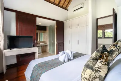 a bedroom with a large bed with a tv on it at D'Maya Villa Jimbaran By Island Escape in Jimbaran