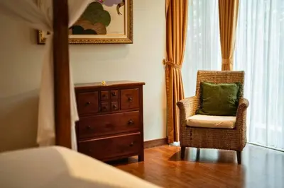 a bedroom with a dresser and a chair with a green pillow at Ghania Peaceful 3 BR Private Pool Villa in Jimbaran