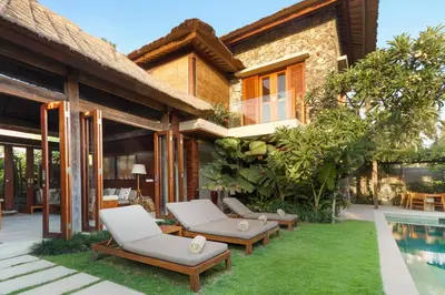a house with two chairs and a swimming pool at Villa Suar Drupadi in Seminyak