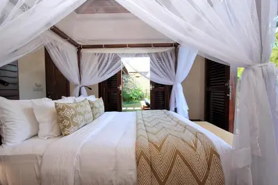 a bedroom with a large white bed with curtains at Villa Suar Drupadi in Seminyak