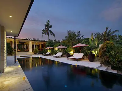 a house with a swimming pool with chairs and umbrellas at Villa Mona in Canggu