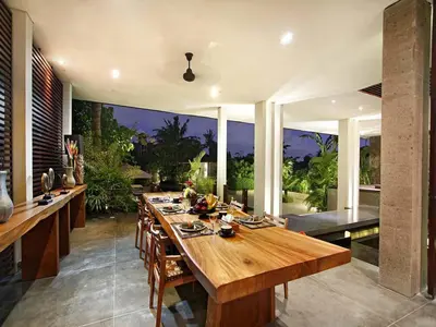 a dining room with a large wooden table with chairs at Villa Mona in Canggu