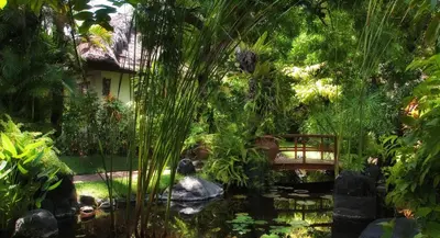 a pond in a garden with a bridge and a pond sidx sidx at Poppies Bali in Kuta