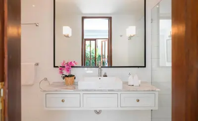 a white bathroom with a sink and a mirror at Villa Merah in Seminyak
