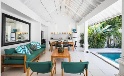 a living room with a table and chairs and a pool at Villa Merah in Seminyak