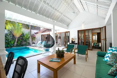 a living room with a couch and a table and a pool at Villa Merah in Seminyak