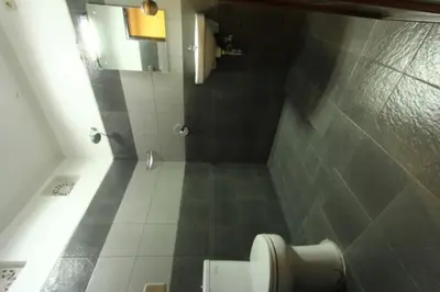 a bathroom with a toilet and a tiled floor at De Dukuh Guest House in Kuta