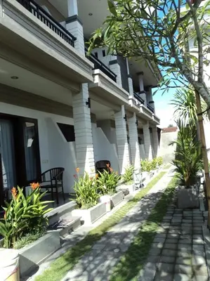 a white building with plants on the side of it at De Dukuh Guest House in Kuta