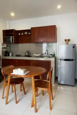 a kitchen with a wooden table and a refrigerator at Villa Sammy in Seminyak