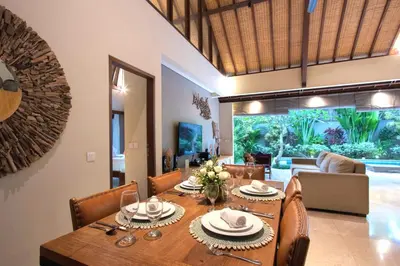a dining room and living room with a table and chairs at Desa Di Bali Villas in Kerobokan