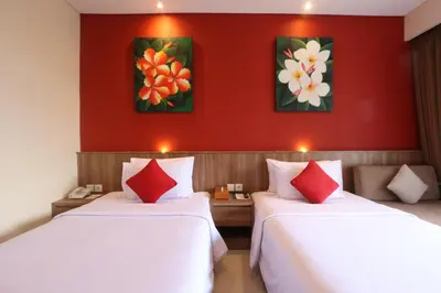 two beds in a hotel room with red walls at Grand La Walon Hotel in Legian